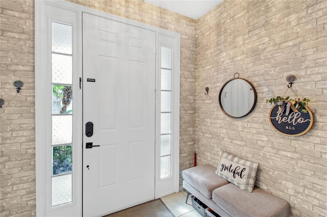 tiled foyer featuring plenty of natural light and brick wall