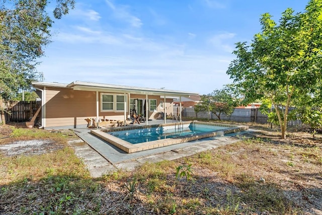 rear view of property with a fenced in pool and a patio