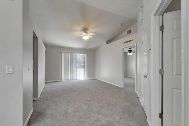 spare room featuring light colored carpet, vaulted ceiling, and ceiling fan