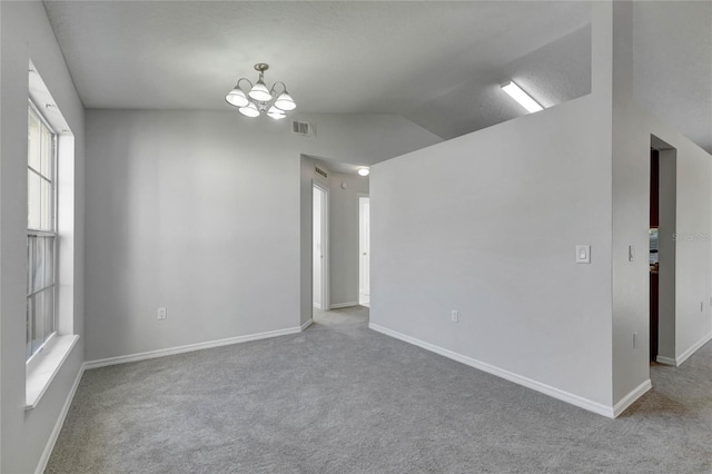 carpeted empty room with a textured ceiling, a notable chandelier, and lofted ceiling