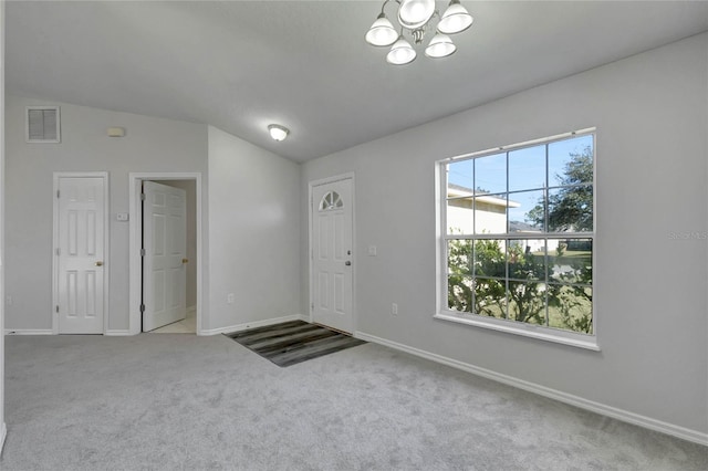 entrance foyer featuring vaulted ceiling, a chandelier, and carpet floors