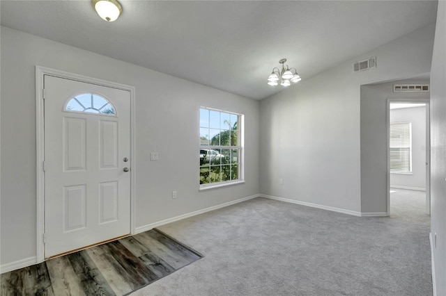 foyer with a chandelier, vaulted ceiling, and carpet floors