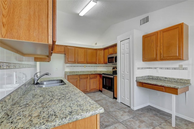 kitchen with vaulted ceiling, a textured ceiling, sink, stainless steel appliances, and light stone counters