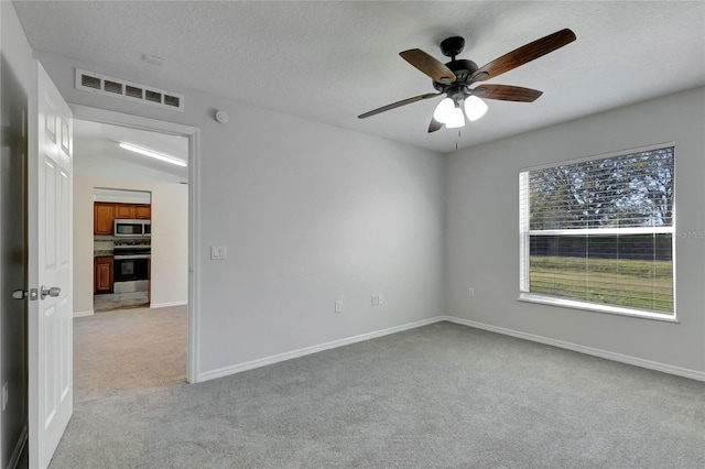 empty room featuring ceiling fan, a textured ceiling, vaulted ceiling, and light carpet