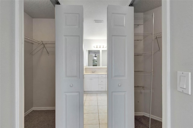 spacious closet featuring sink and tile patterned floors