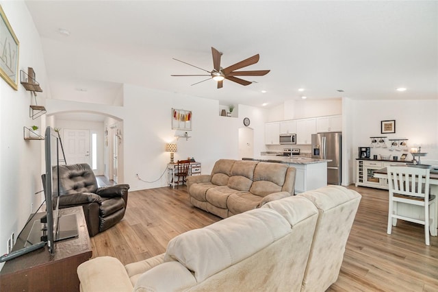 living room featuring ceiling fan, light hardwood / wood-style floors, and vaulted ceiling