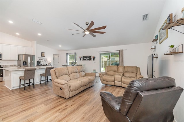 living room featuring ceiling fan, light hardwood / wood-style floors, and vaulted ceiling