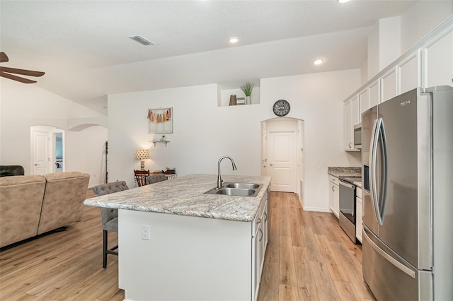 kitchen featuring appliances with stainless steel finishes, light wood-type flooring, sink, a center island with sink, and white cabinetry