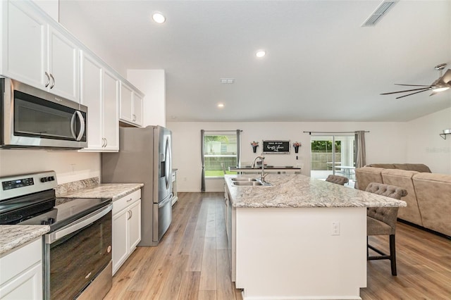 kitchen featuring white cabinets, stainless steel appliances, a kitchen island with sink, and sink