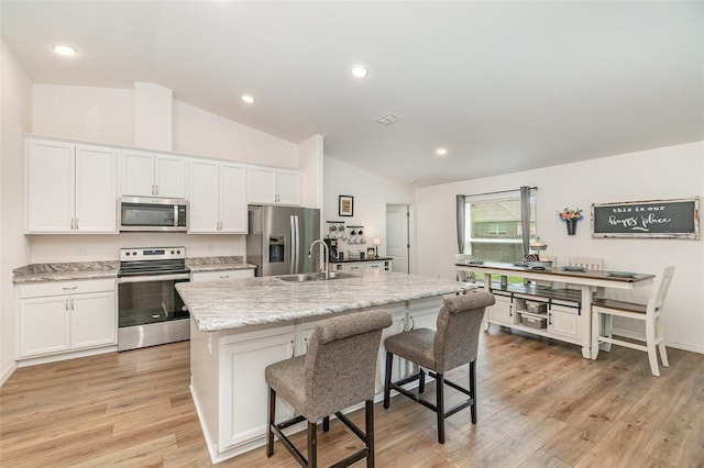 kitchen featuring white cabinets, sink, stainless steel appliances, and a kitchen island with sink