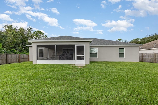 rear view of house featuring a lawn and a sunroom