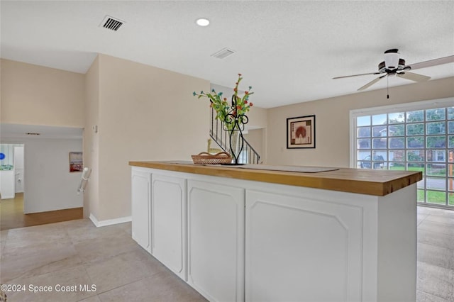 kitchen with white cabinets, light tile patterned floors, ceiling fan, and butcher block counters