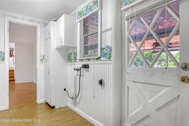 laundry room with light hardwood / wood-style floors and crown molding