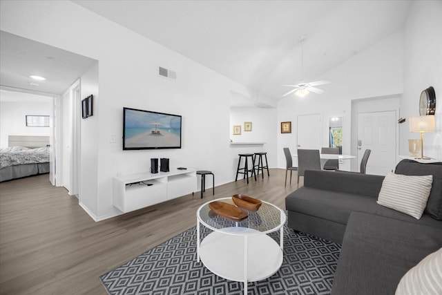 living room with wood-type flooring, high vaulted ceiling, and ceiling fan