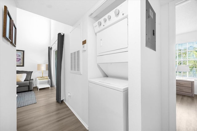 laundry room featuring hardwood / wood-style flooring and stacked washer and clothes dryer