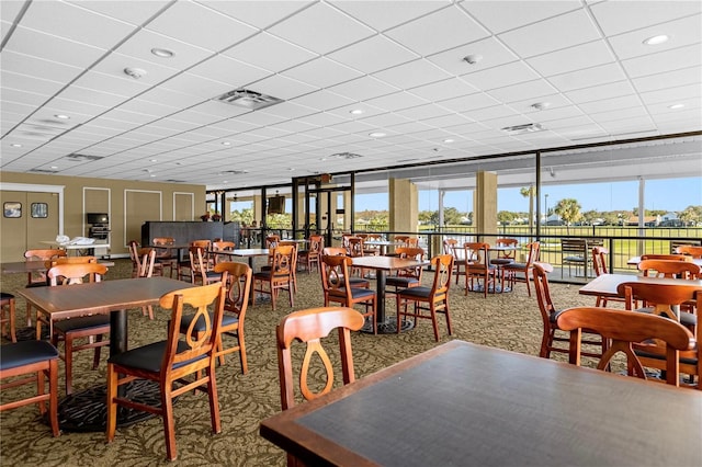 carpeted dining area with a drop ceiling