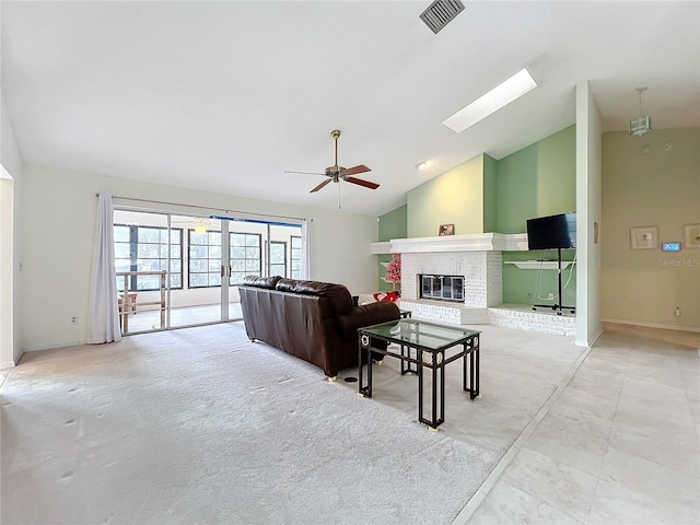 living room with ceiling fan, light colored carpet, lofted ceiling with skylight, and a brick fireplace