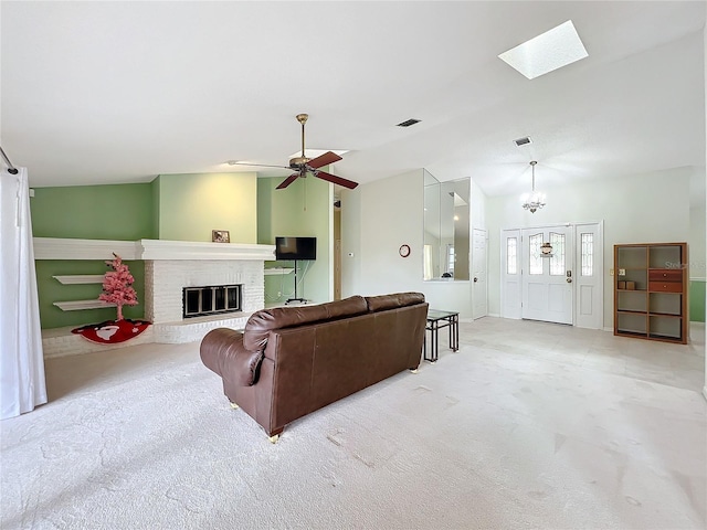 living room with lofted ceiling with skylight, light carpet, ceiling fan with notable chandelier, and a brick fireplace