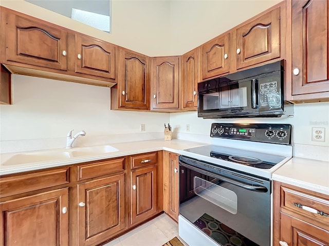 kitchen with white electric range, light tile patterned floors, and sink