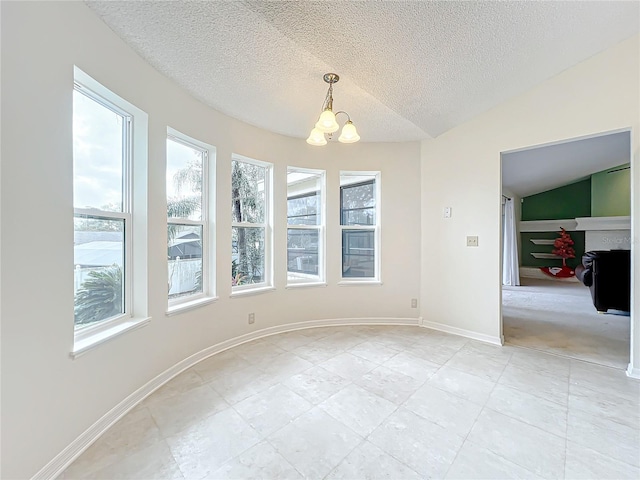 empty room with a textured ceiling, vaulted ceiling, and a notable chandelier