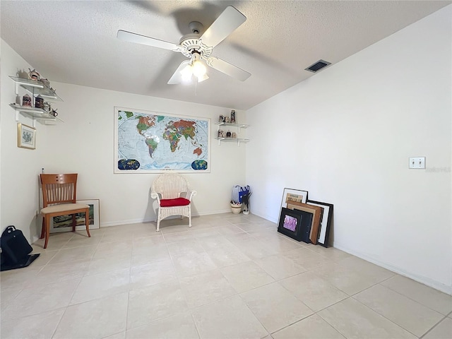 living area with a textured ceiling, ceiling fan, and light tile patterned flooring