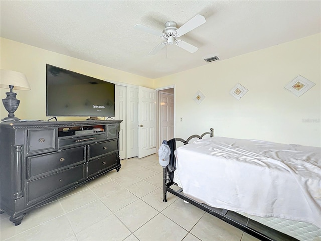 bedroom with ceiling fan, light tile patterned floors, and a textured ceiling