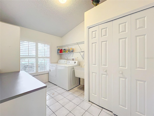 washroom with washing machine and dryer, light tile patterned floors, and a textured ceiling