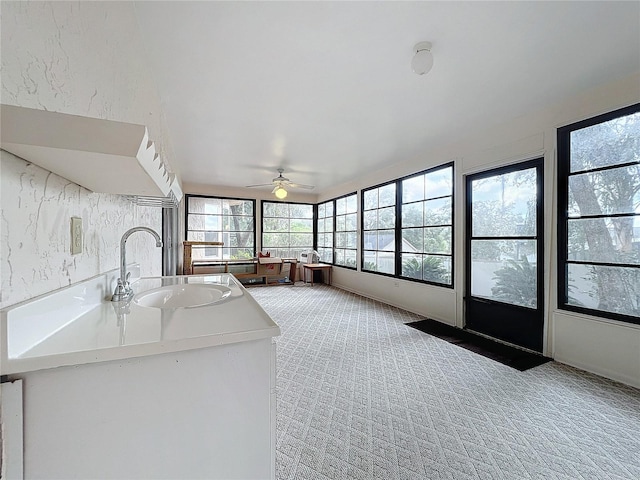 unfurnished sunroom featuring ceiling fan and sink