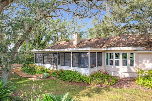 rear view of house featuring a lawn and a sunroom