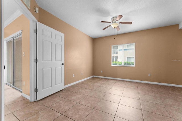 spare room with ceiling fan and light tile patterned floors