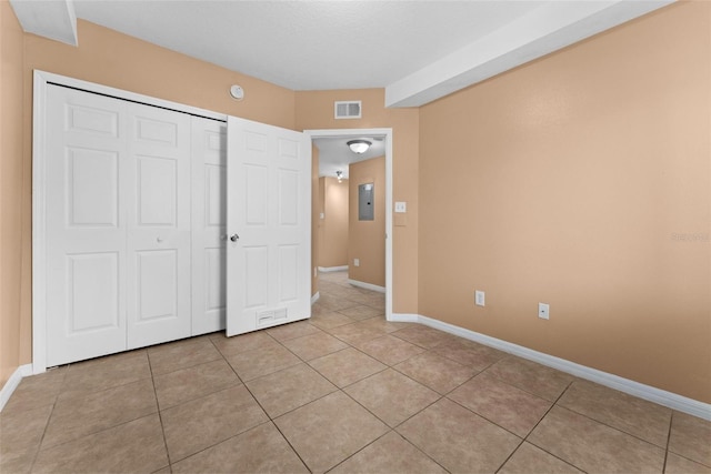 unfurnished bedroom featuring light tile patterned floors, electric panel, and a closet