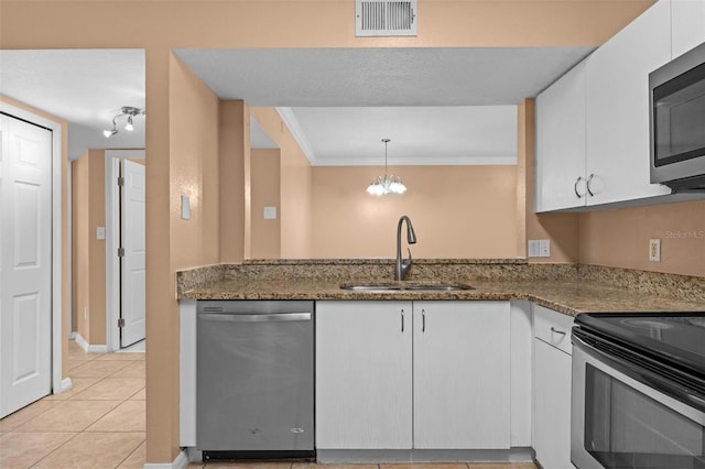 kitchen featuring sink, stainless steel appliances, dark stone counters, pendant lighting, and white cabinets