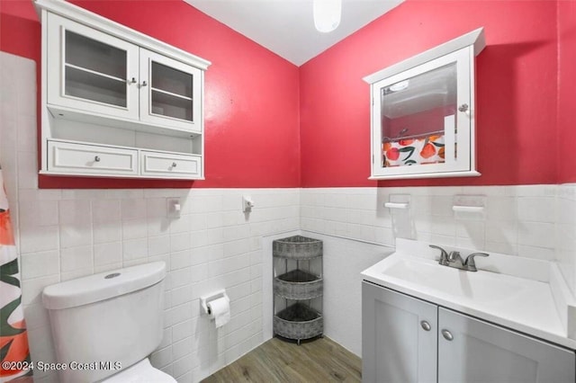 bathroom with hardwood / wood-style flooring, vanity, toilet, and tile walls