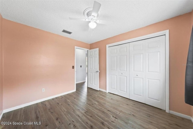 unfurnished bedroom with ceiling fan, a closet, a textured ceiling, and hardwood / wood-style flooring