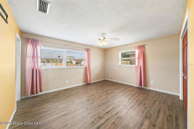 empty room featuring wood-type flooring, a textured ceiling, plenty of natural light, and ceiling fan