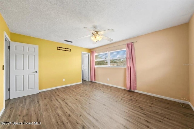 unfurnished room featuring hardwood / wood-style flooring, ceiling fan, and a textured ceiling