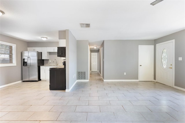 kitchen with white cabinetry, stainless steel fridge with ice dispenser, sink, and light tile patterned floors