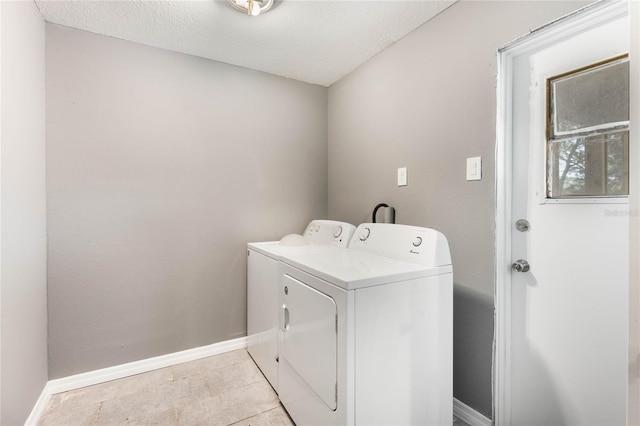 clothes washing area with separate washer and dryer, light tile patterned flooring, and a textured ceiling