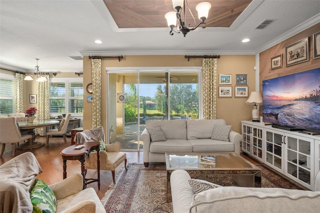 living room with hardwood / wood-style floors, an inviting chandelier, and crown molding