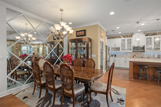 dining space featuring ornamental molding, light hardwood / wood-style flooring, and a notable chandelier