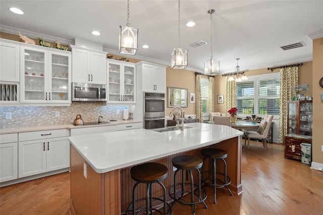 kitchen featuring white cabinets, stainless steel appliances, and a center island with sink