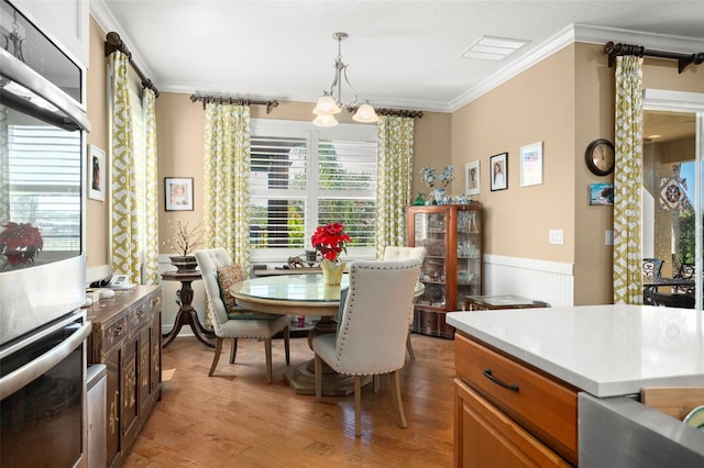 dining space featuring a chandelier, a textured ceiling, light hardwood / wood-style flooring, and ornamental molding