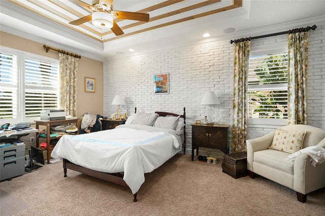 bedroom with a raised ceiling, ceiling fan, crown molding, and brick wall