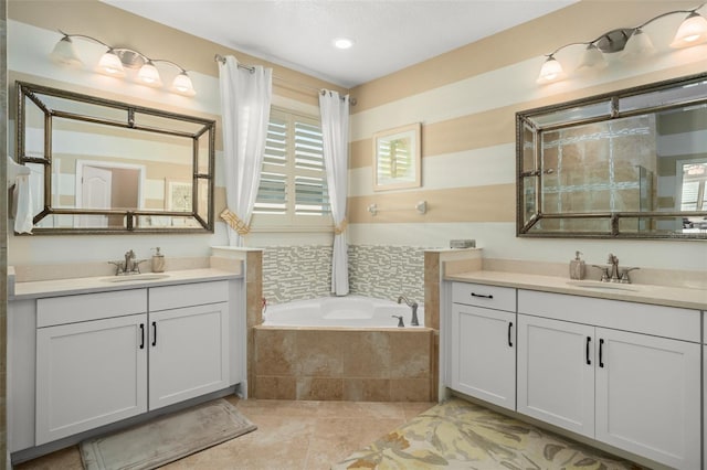 bathroom with tile patterned floors, a relaxing tiled tub, and vanity