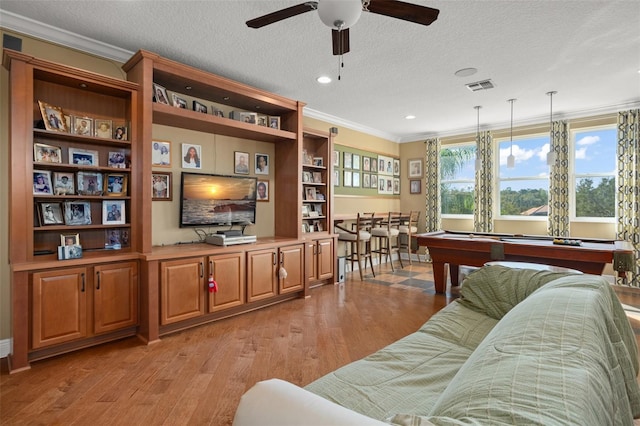 living room featuring ornamental molding, light wood-type flooring, a textured ceiling, and pool table