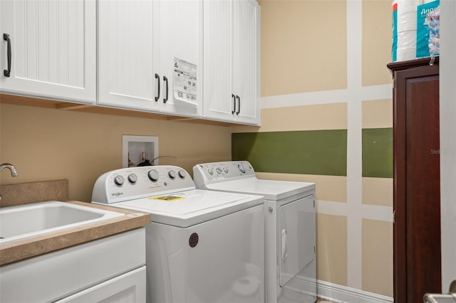 clothes washing area featuring cabinets, sink, and washer and dryer