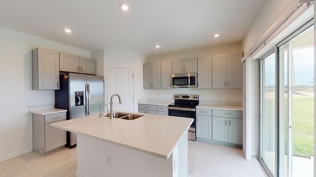 kitchen featuring gray cabinets, sink, appliances with stainless steel finishes, and an island with sink