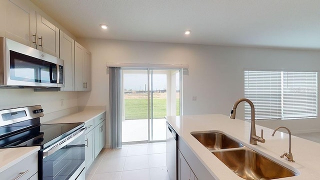 kitchen with light tile patterned floors, stainless steel appliances, white cabinetry, and sink