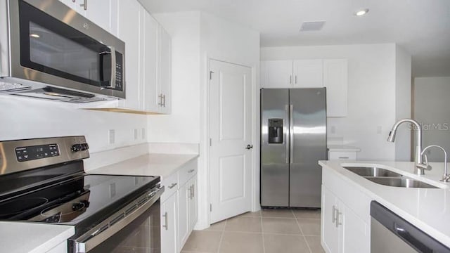 kitchen with light tile patterned flooring, sink, white cabinetry, and stainless steel appliances