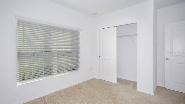 unfurnished bedroom featuring light carpet and a closet